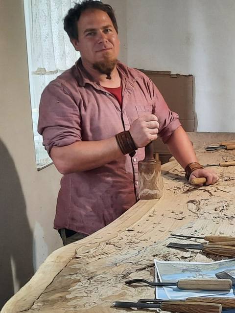 Stephan mit Klüpfel und Schnitzeisen an der Tischplatte